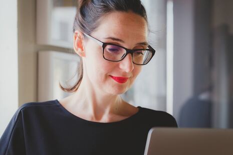 photo d'une femme portant des lunettes et regardant son écran d'ordinateur