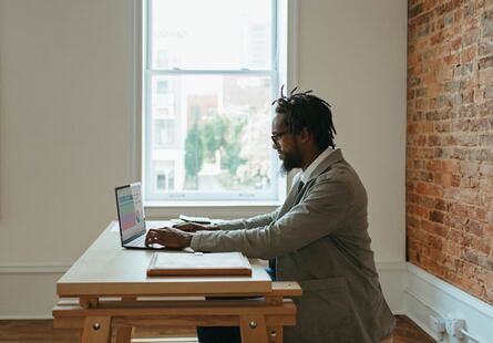personne assise à un bureau tapant sur le clavier d'un ordinateur